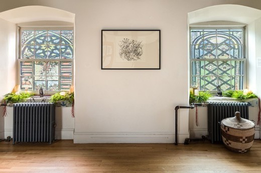 A framed artwork sits between two stained-glass windows.